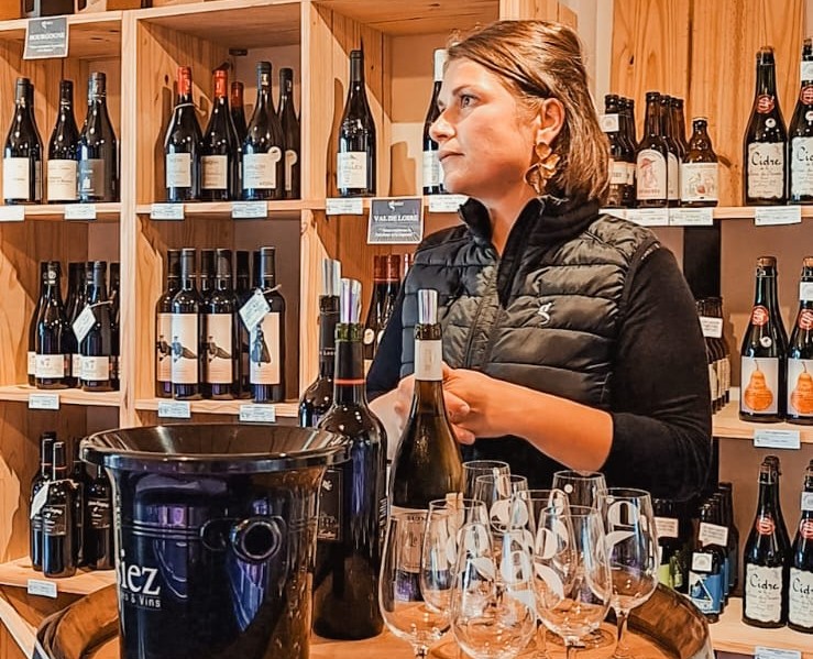 Claire présente une sélection de vins autour d’un tonneau, lors d'une dégustation dans la boutique de La Guerche-de-Bretagne